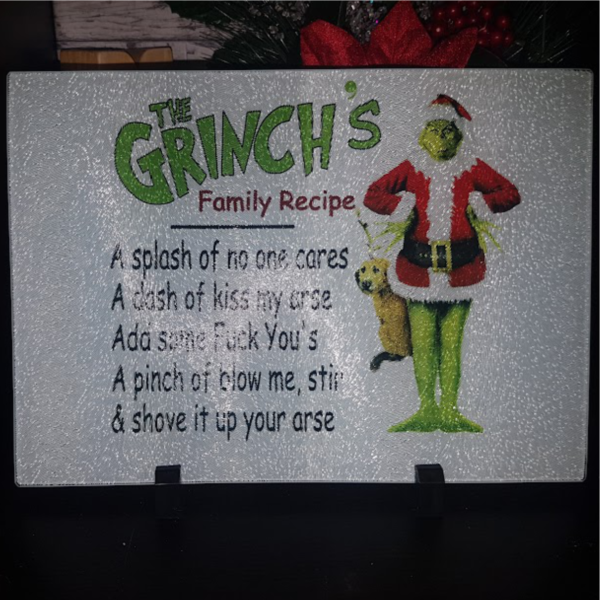 "8x11 glass cutting board featuring a Grinch's Family Recipe design in vibrant colors. Durable, heat-resistant, and festive, perfect for holiday cooking or decor."